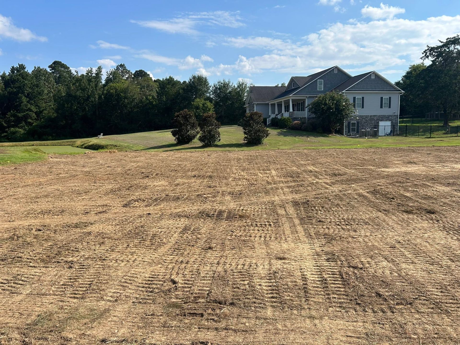 Finished backyard regrade with fresh pad and the house on the hill behind