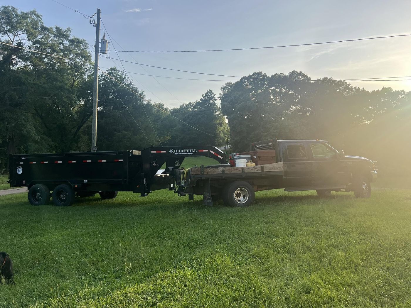 Dually truck hitched to a gooseneck dump trailer at sunset
