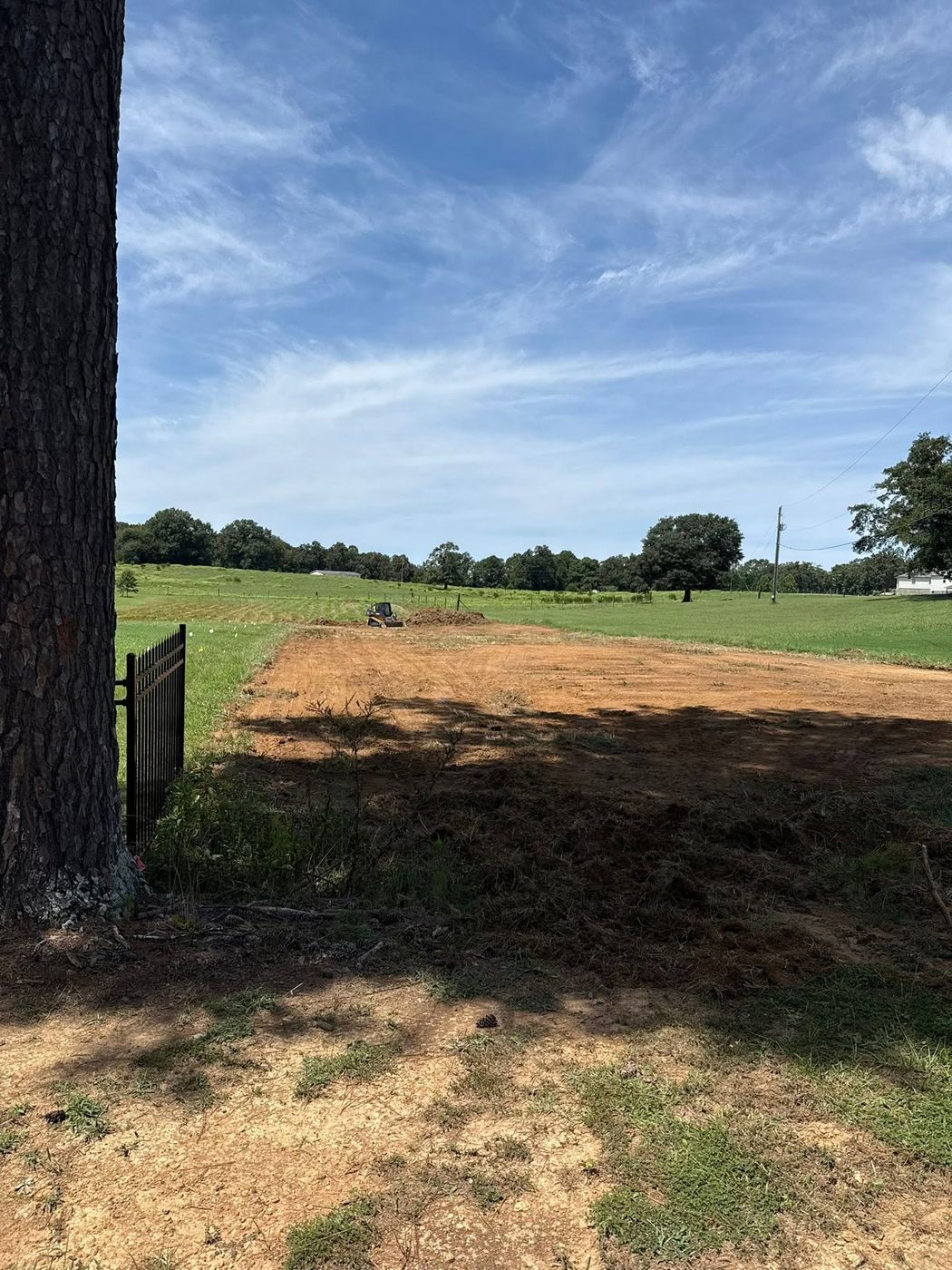 Track loader cutting a pad in a pasture