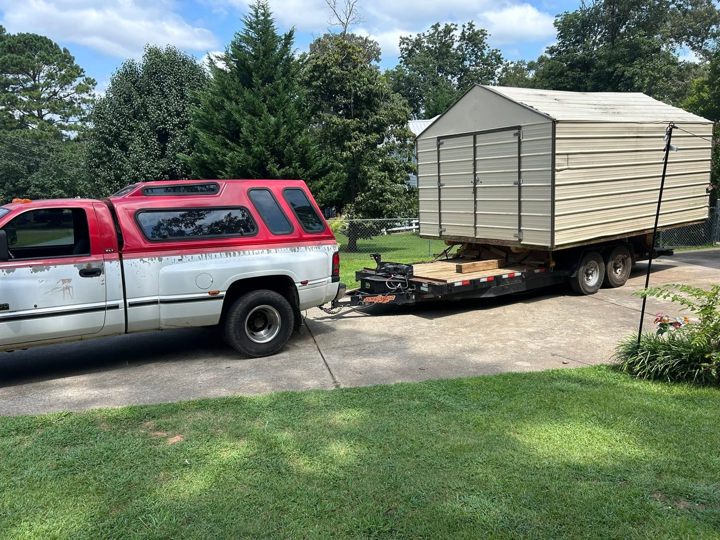 Storage building loaded on a tilt trailer